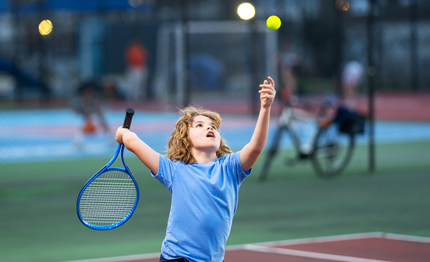 Child serving a tennis ball